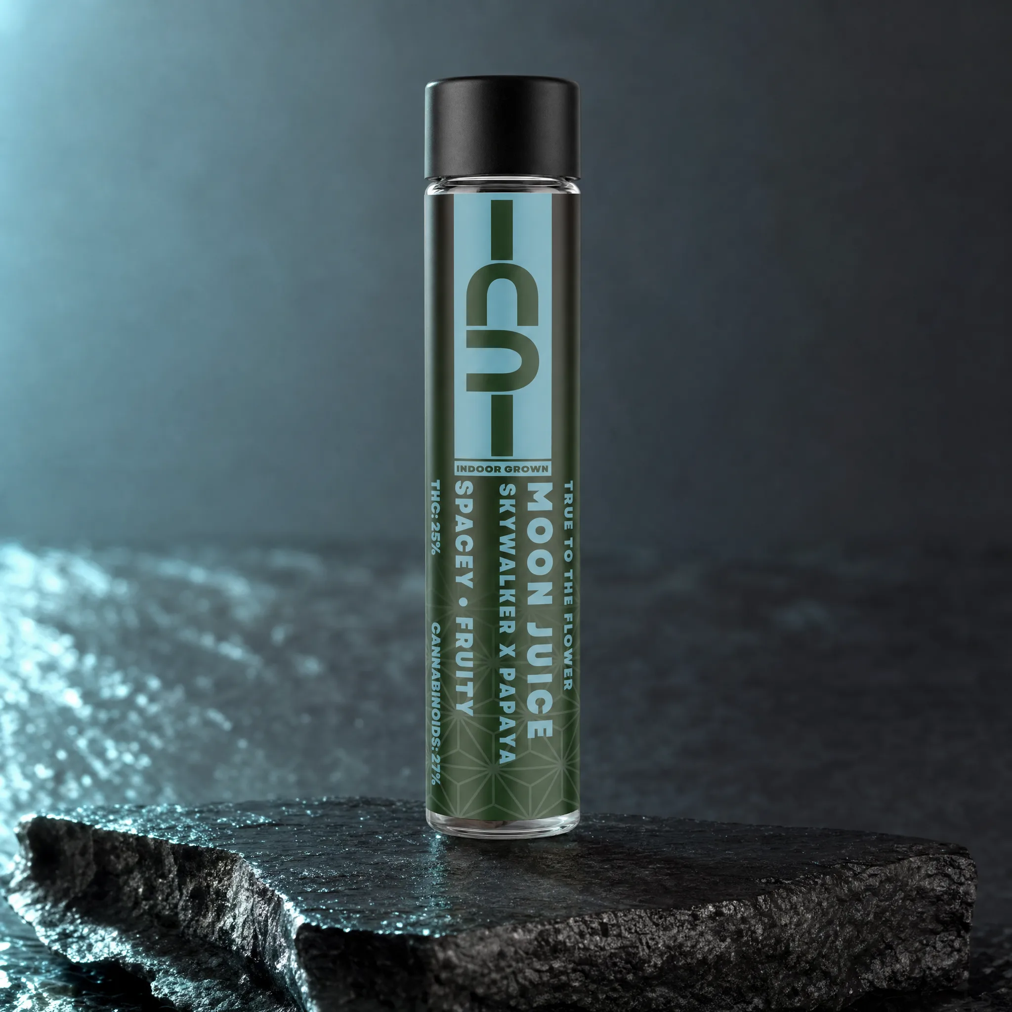 Moon Juice hybrid pre-roll in a clear glass tube on dark wet basalt, teal and forest-green CU label